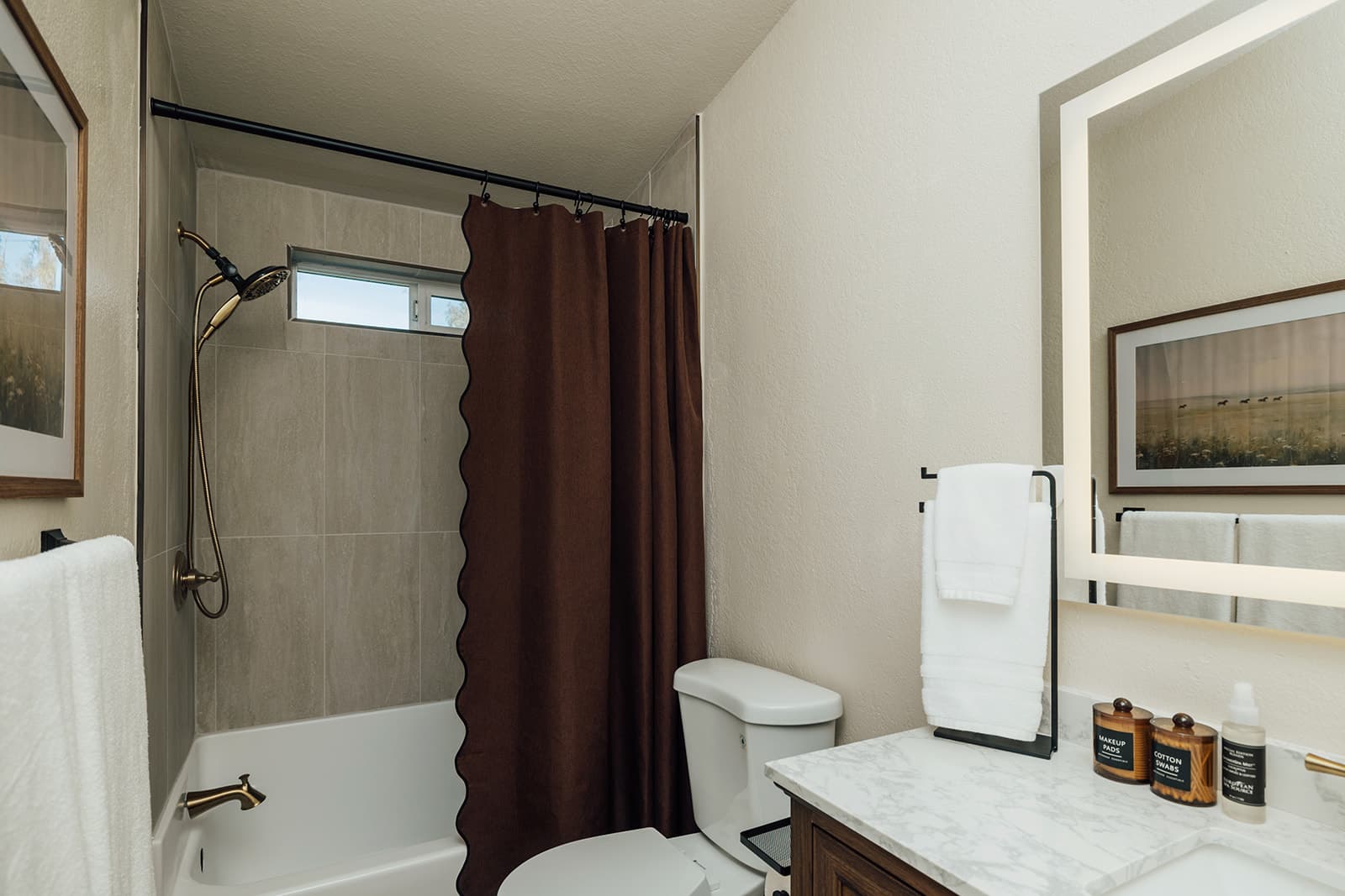 Guest bathroom with a tub-and-shower combo and a lit vanity mirror