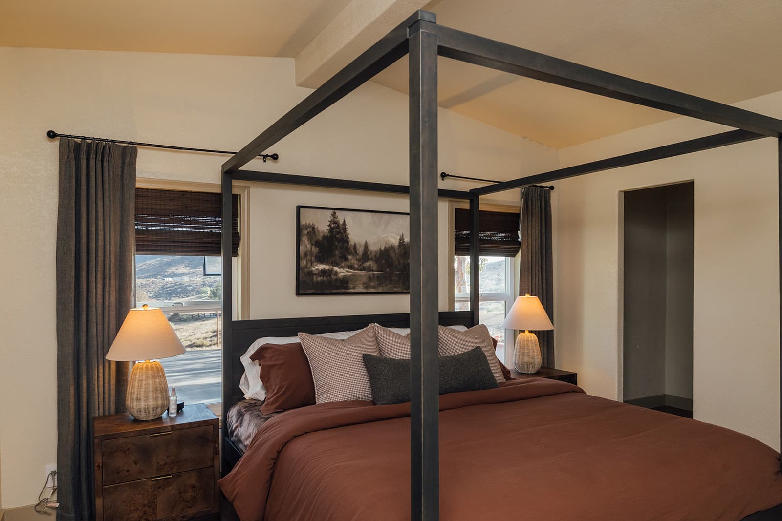 Primary suite with an iron canopy king bed and hill-country views