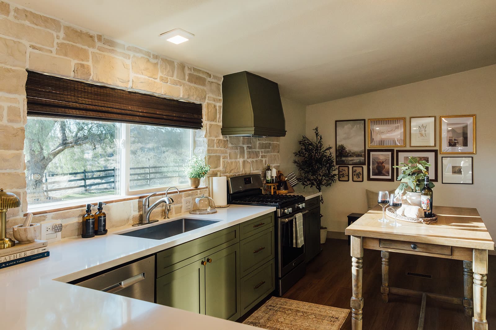 Gourmet kitchen with olive cabinetry, a stone accent wall, and a farmhouse dining table
