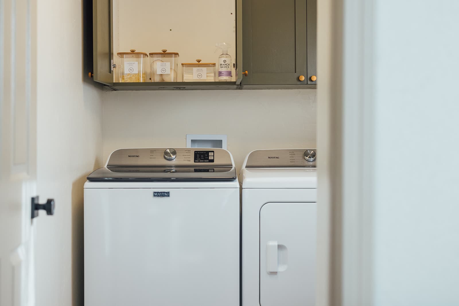 Laundry room with a full-size washer and dryer and stocked supplies